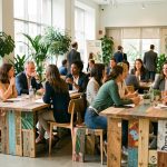 Des femmes et des hommes participent à un événement professionnel écoresponsable dans un lieu lumineux entouré de végétation et aménagé avec des matériaux réemployés.
